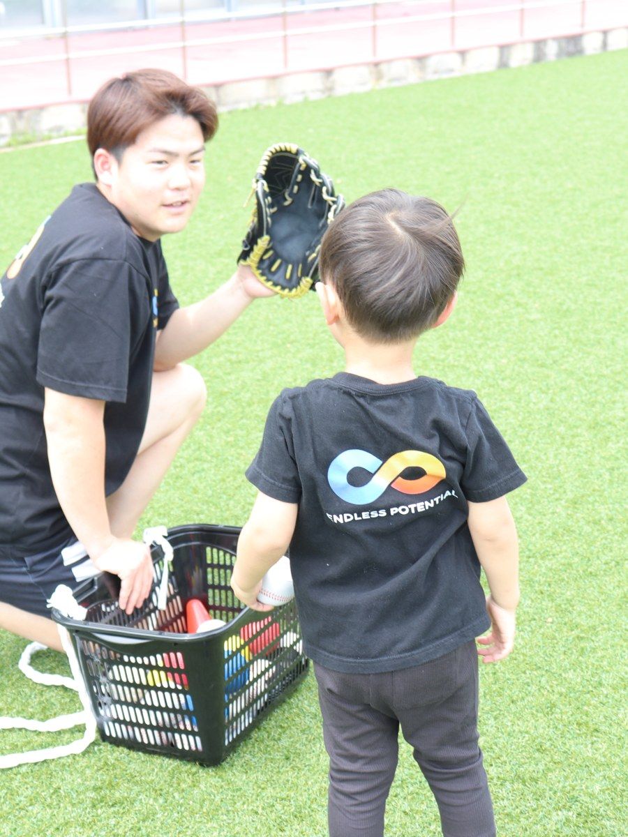 グローブでボールを捕る練習をするコーチと子ども