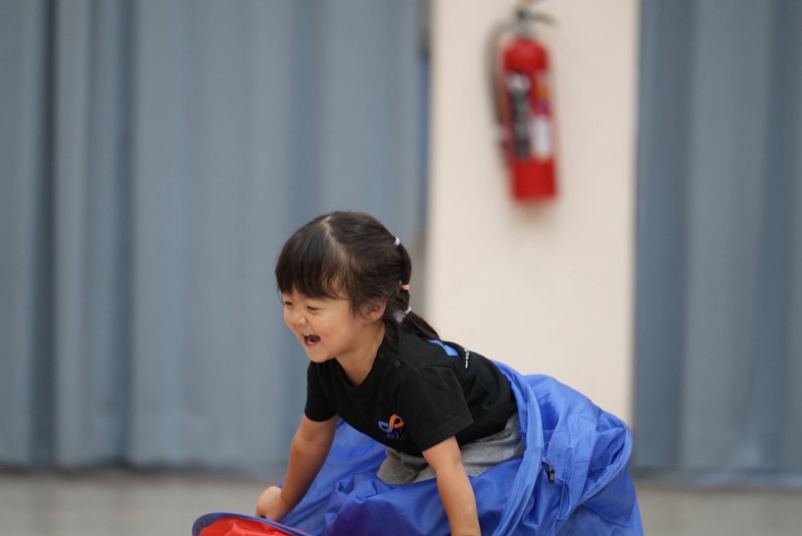トンネル遊びで笑顔になる2歳の子ども